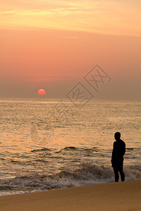 日落时人类在宁静的海滩上凝高清图片