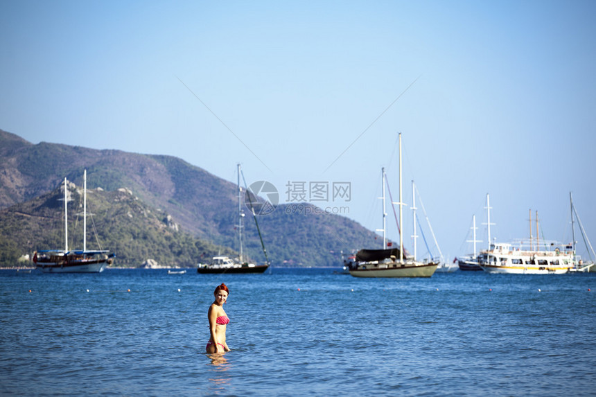 美丽的年轻女子站在海上夏天的图片