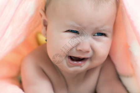 小女孩在粉红色毯子下哭泣的肖像图片