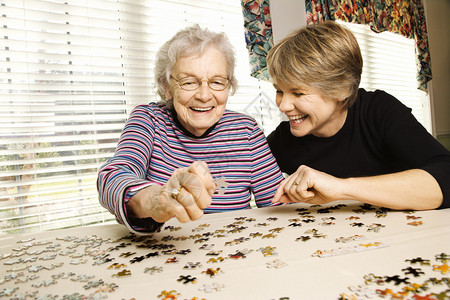 老年妇女和年轻的女人做拼图图片