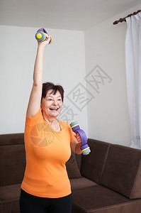 微笑成熟的成年健身妇女在家里用巴铃割开生殖器图片
