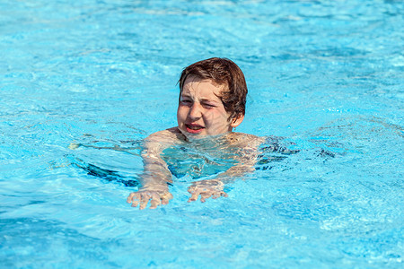 在游泳池游泳的可爱男孩图片