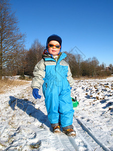 快乐的小男孩在雪地上玩耍图片