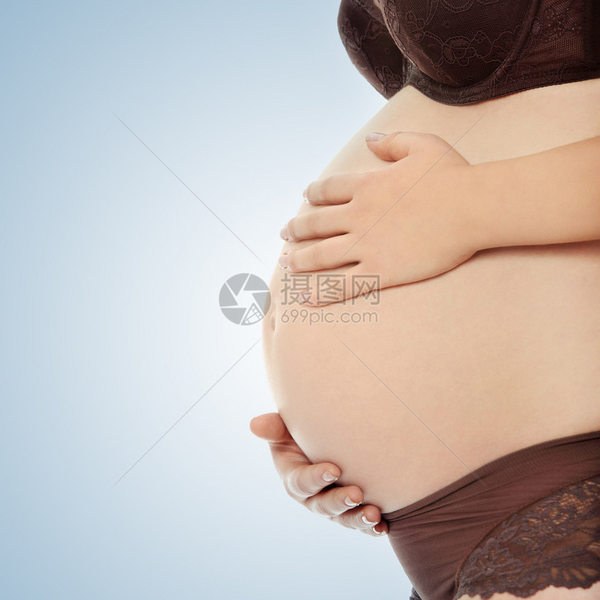 一个孕妇的肚子她的手放在它上面图片