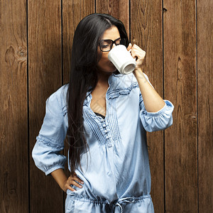 一位美丽的年轻女子的肖像喝咖啡在杯子上和图片