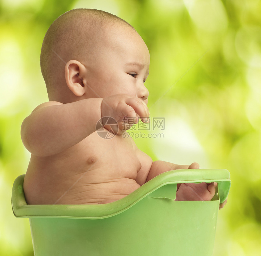 小婴儿在户外的浴缸里洗澡图片