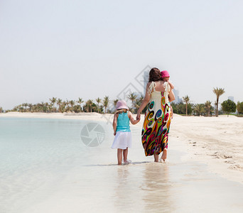 母亲和她的两个小女儿在沙滩上散步图片