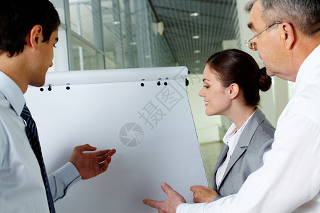 3个商业伙伴在会议上指和注视白板并举图片