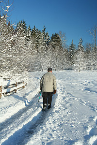 一位年长的绅士独自走过白雪覆盖的公园图片