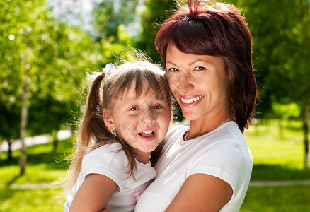 快乐的年轻母亲与美丽的小女儿一起在公园中欢笑图片
