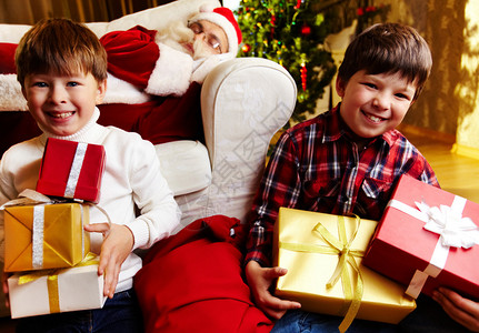 照片来自喜悦的男孩拿着礼物与圣诞老人一图片
