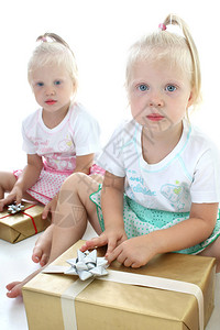 双胞胎在白色包装礼物图片