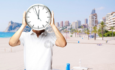 一个人拿着时钟靠在海滩上的肖像图片