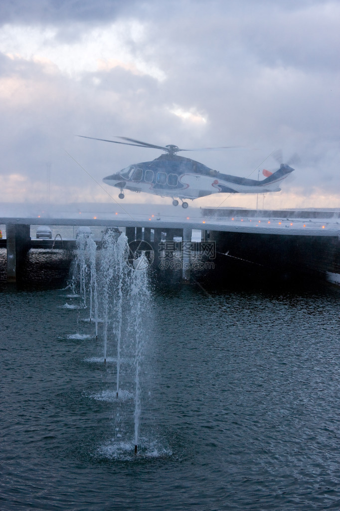 雪暴中客用直升机从喷泉后面的平台上起飞的照片图片
