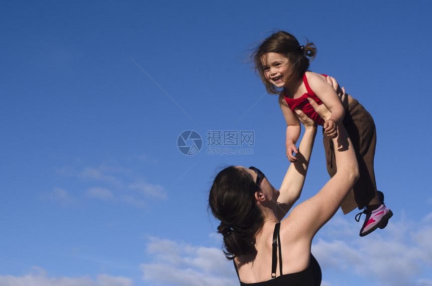 一个年轻母亲将她幸福的女儿抱在空中图片