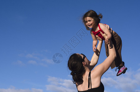 一个年轻母亲将她幸福的女儿抱在空中图片