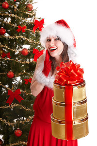 穿着圣塔帽的女孩在圣诞树附近拿着书架礼物图片