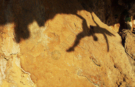 一位女攀岩者在悬崖上的影子图片