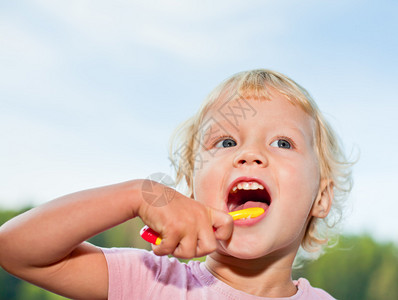 可爱的小女孩在户外刷牙的肖像图片
