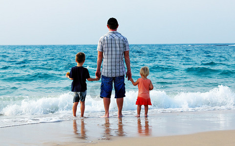 父亲带着两个孩子在海上度假图片