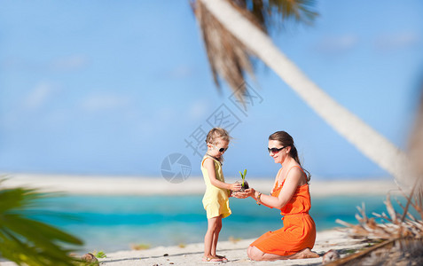 母亲和女儿在热带海滩有小椰子图片