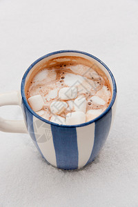 一杯热巧克力和雪地上融化的棉花糖背景图片