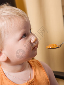 蹒跚学步的男孩脸脏用茶匙吃东西图片