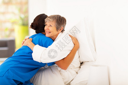快乐老人的女人在床上拥抱照料者图片