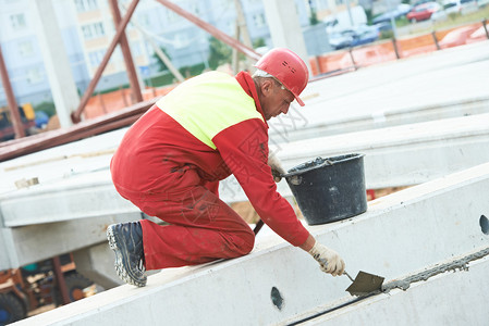 建筑施工现场安全防护设备中的建筑工人将水泥砂浆放在混凝土楼板上图片