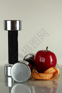 灰色背景上带苹果和厘米的哑铃图片