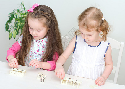两个小女孩在桌子上玩多米诺骨牌图片
