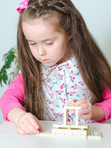 小女孩在桌子上玩多米诺骨牌图片