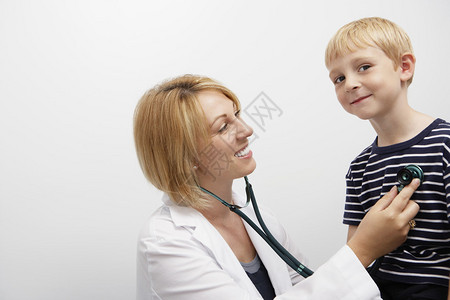 女医生在诊所用听诊器检查白种男孩的图片