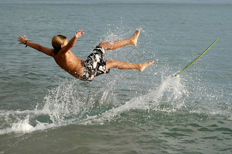 男孩用滑板在海浪中冲浪图片