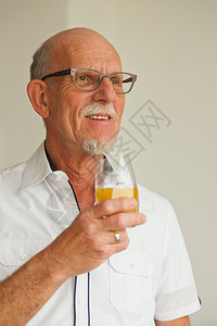 戴眼镜的老人在客厅里喝橙汁图片