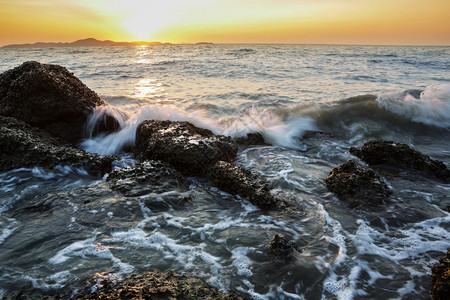 泰国芭堤雅海滩日落时海浪击中岩石图片