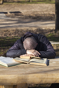学生躺在外面的长凳上的书上睡着了图片