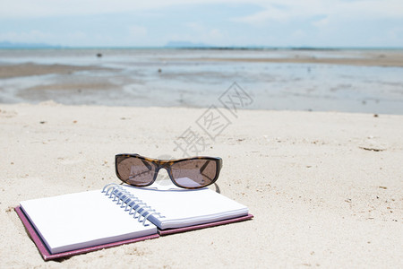 躺在海滩上的笔记本和太阳镜图片