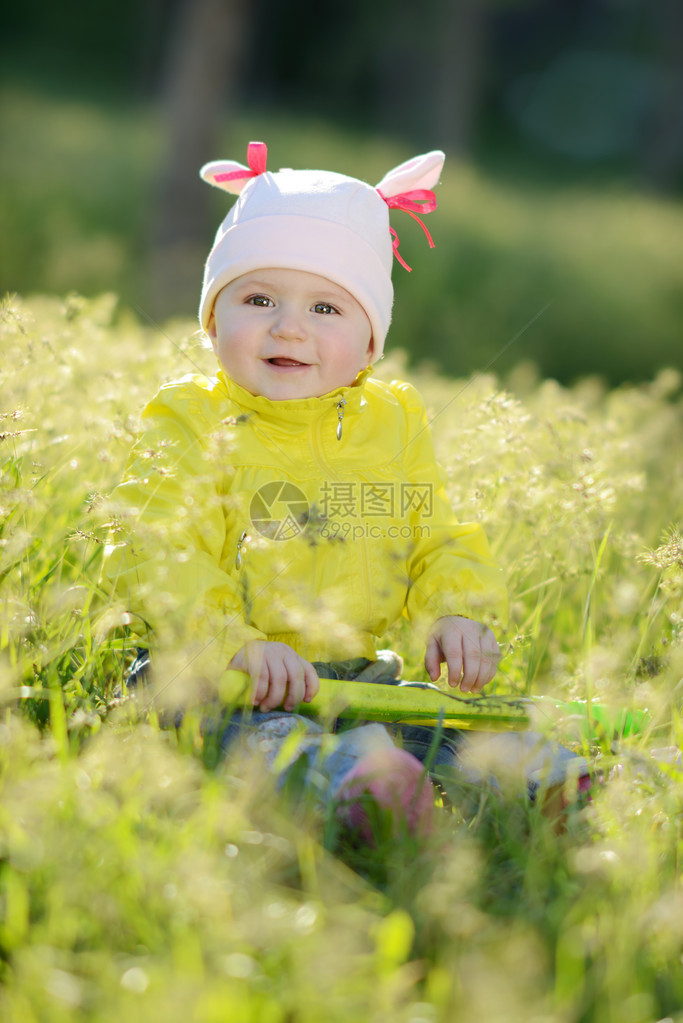 坐在阳光明媚的草地上的快乐宝贝图片