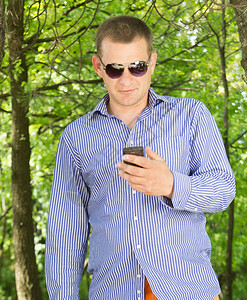 青年男子在穿过绿林时使用电话图片