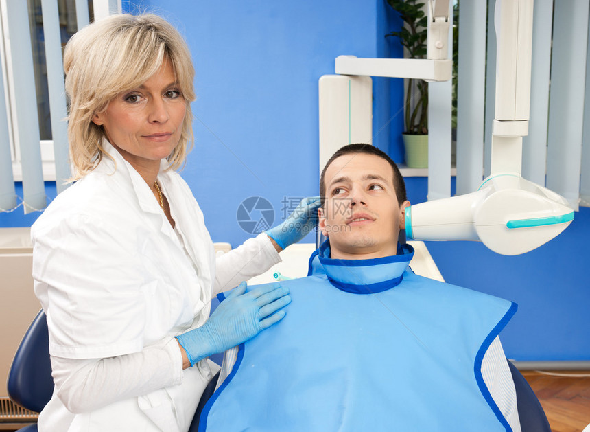 女牙医用X光机检查男患者牙齿图片