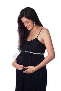 一个美丽的年轻孕妇的肖像俯视着她的肚子满怀期待图片