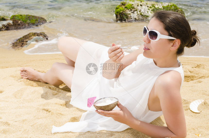 美丽的女人在海滩上拿着冰淇淋图片