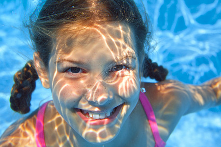 可爱女孩在水下游泳并微笑图片