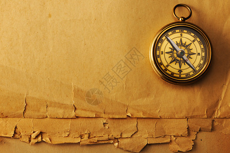 在旧纸背景的古董黄铜指南针图片