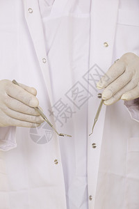 一名牙医手拿白手套和牙科工具手持图片