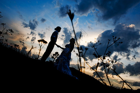 日落背景下年轻新娘和新郎的剪影图片