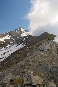 登山者在雄伟的高山背景下的落基山脊上徒步上山图片