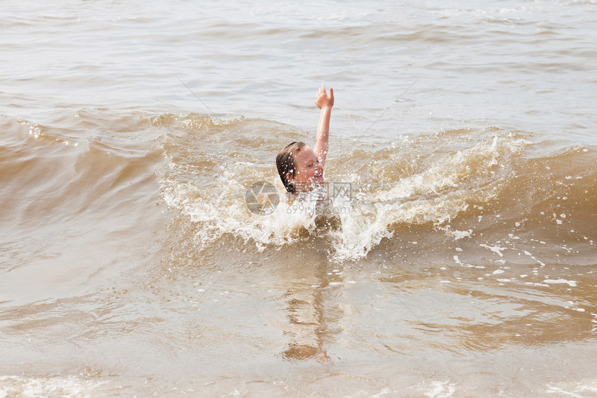 在海浪中玩耍的单身小男孩图片