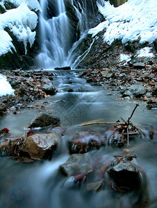 冬天的夜景冰柱和冰冷的巨石进入溪流图片
